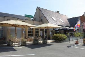 eine Terrasse mit Sonnenschirmen und Stühlen vor einem Gebäude in der Unterkunft Hostellerie Daiseldaele in Dadizele
