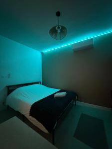 a dark room with a bed with a blue light at Le Brun - T1 climatisé - Terrasse et jardin privé in Agen