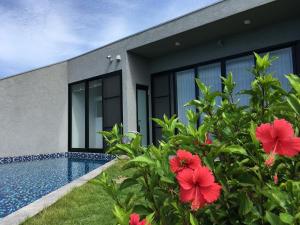 a house with a swimming pool and red flowers at Hanalee Villa Kouri in Nakijin