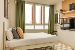 a bedroom with a bed and a window with green curtains at Appart'hôtel Toulouse Zénith in Toulouse