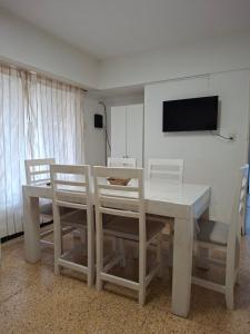 a white dining room table with chairs and a television at Los Dias de Viaje in Tandil
