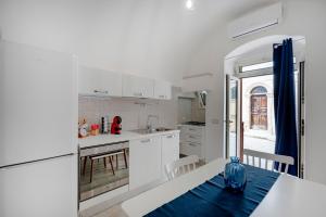 a kitchen with white cabinets and a blue vase on a table at Case D'Amare - Tritone 30 in Polignano a Mare