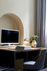a computer monitor sitting on a desk with a chair at BB Hotels Smarthotel Missori in Milan