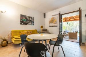 a living room with a table and chairs and a yellow couch at Estay - Casa Madili - Garden - BBQ - WiFi in Sarroch