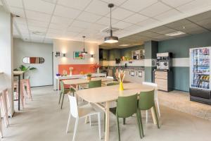 a dining room and kitchen with tables and chairs at Appart'hôtel Toulouse Zénith in Toulouse