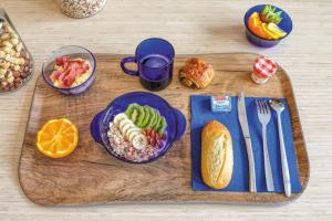 a table with a cutting board with breakfast food on it at Appart'hôtel Toulouse Zénith in Toulouse