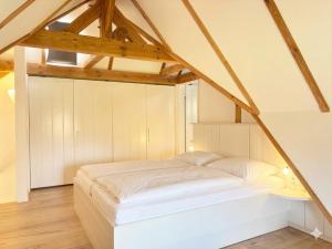 a white bed in a room with wooden ceilings at Rosenhaus - Lütt Arnis in Arnis