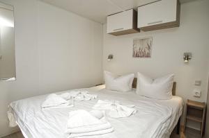 a white bed with white towels on top of it at Tiny Home Strandkoje 823 in Göhren