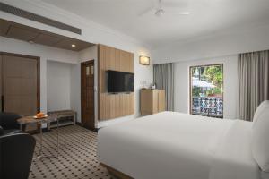 a hotel room with a white bed and a television at Radisson Goa Candolim in Candolim