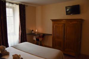 a bedroom with a bed and a cabinet and a television at Hôtel-Restaurant Au Moulin d'Alexandre in Sainte-Eulalie-dʼOlt