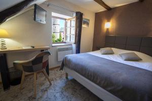 a bedroom with a bed and a desk and a window at Hôtel-Restaurant Au Moulin d'Alexandre in Sainte-Eulalie-dʼOlt