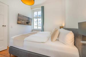 a bedroom with a bed with white sheets and a window at Villa Tanneck App 1 in Ahlbeck
