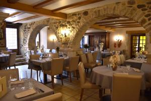 a restaurant with tables and chairs and a stone wall at Hôtel-Restaurant Au Moulin d'Alexandre in Sainte-Eulalie-dʼOlt