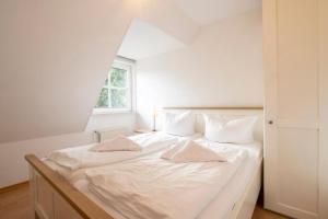 a white bed in a room with a window at Ayuna in Langeoog