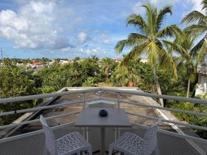 a balcony with a table and chairs and palm trees at Residence Anse des sables in Marigot +1 photo