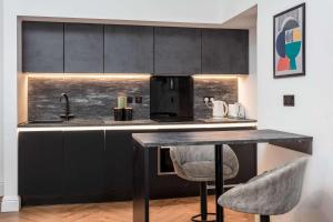 a kitchen with black cabinets and a table with two chairs at The Fairlie Suite No1 in Prestwick