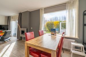 a dining room with a wooden table and red chairs at Californiëweg 9A in De Koog