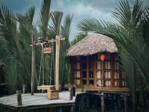 a small house with a straw roof on a wooden platform at Bonomali Mangrove Resort in Dhāngmāri Forest Office