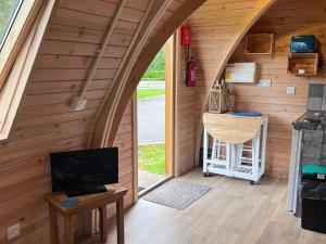 a room in a tiny house with a tv and a desk at Lakeside Pods - pets welcome in Oldham