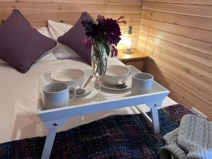 a tray with cups and a vase with flowers on a bed at Lakeside Pods - pets welcome in Oldham +8 photos