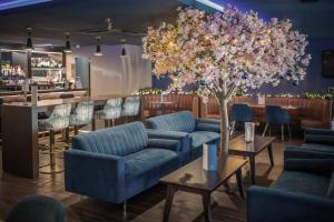 a lobby with blue couches and a tree and a bar at The Kinmel & Kinspa in Abergele
