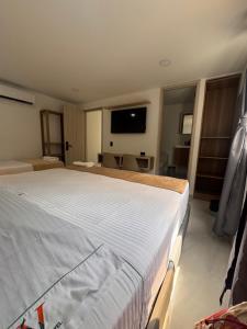 a bedroom with a large white bed with a flat screen tv at Vida Hostel in Medellín