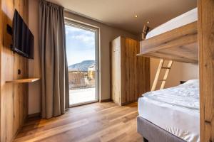 ein Schlafzimmer mit einem Etagenbett und einem großen Fenster in der Unterkunft EGGER Apartments & Suites in Villanders + 66 Fotos