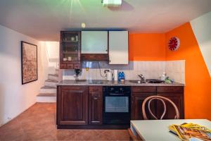 a kitchen with wooden cabinets and an orange wall at Centovalli Rustic near Locarno in Intragna +22 photos