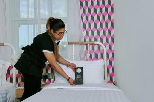 a woman standing next to a bed with a clock on it at The California - Kings Cross St Pancras, London in London