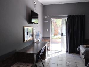 a living room with a desk and a sliding glass door at Windpomp Guesthouse in Beaufort West