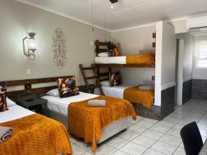 a room with three bunk beds with orange blankets at Windpomp Guesthouse in Beaufort West