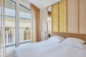 a bedroom with a white bed and a large window at MAISON SAINT CHARLES - ASSOCIATION HABITAT et HUMANISME ILE DE FRANCE in Paris