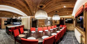 a dining room with a long table and red chairs at Chalet Adelphine 1 & SPA in Les Gets