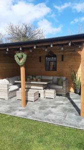 a patio with couches and chairs under a roof at Coastal Rest in Beadnell