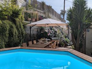 a swimming pool with a table and an umbrella at Charmant haut de villa in Châteauneuf
