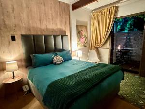 a bedroom with a green bed and a window at Naby-My Stellenbosch Cottage in Stellenbosch