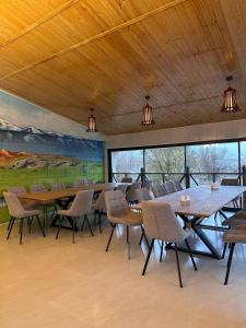 a dining room with tables and chairs and a painting at Гостиница Asan Ali in Kapchagay