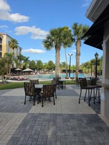 a patio with tables and chairs and palm trees at Pura Vida in Orlando