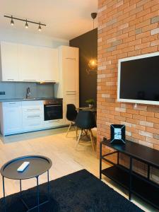 a living room with a television and a brick wall at Tarnowskiego City Apartaments in Kutno