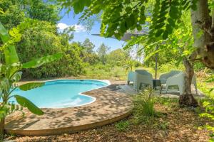 a swimming pool in a garden with chairs around it at Canopy Lodge - Perfect Mauritius Trip in Tamarin