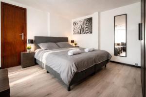 a bedroom with a large bed and a wooden floor at Le Studio by La Reine City Center in Spa