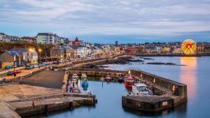 a city with a ferris wheel and boats in the water at Anchorage Inn in Portstewart +30 photos