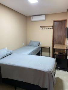 a room with two beds and a television in it at Hotel Lorenna in Santa Inês