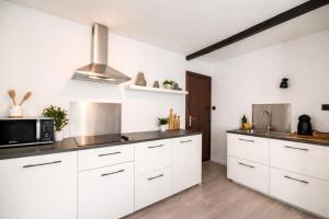 a kitchen with white cabinets and a microwave at Le Studio by La Reine City Center in Spa