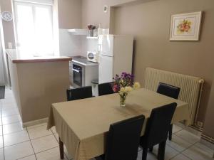 a kitchen with a table with chairs and a white refrigerator at Gîte simone de beauvoir in Châteauvillain