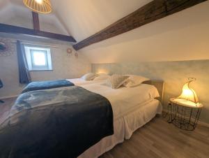 a bedroom with a large bed and a lamp at Gîte simone de beauvoir in Châteauvillain