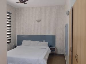 a bedroom with a white bed and a ceiling fan at Transit Care Hotel in Port Harcourt