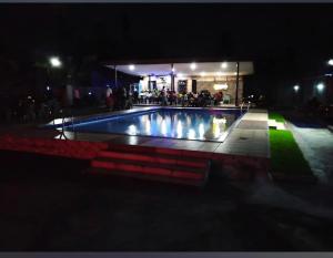 a swimming pool at night with people standing around it at Transit Care Hotel in Port Harcourt