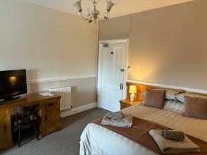 a bedroom with a bed and a desk and a television at The Berkeley Arms Hotel in Berkeley