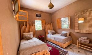 a bedroom with two beds and a mirror and windows at Ouberge 'loassis house in Douar Azrou Melloul